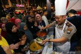 Perwira Polres Lamongan melayani warga yang mengantre makanan saat Pesta Rakyat dan Festival Kuliner bertajuk 