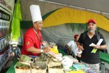 Chef Dodik Prakoso (kiri) asal Indonesia memperkenalkan menu kuliner khas Yogyakarta yang dijualnya kepada seorang wisatawan di stand Sarawak Asia Kitchen pada perhelatan Rainforest World Music Festival 2019 di Sarawak, Malaysia, Sabtu (13/7/2019). Chef Dodik Prakoso menyatakan selama empat tahun terakhir Ia telah menyajikan menu kuliner khas Yogyakarta seperti Gudeg Yogya komplit dan Bakpia untuk dinikmati para wisatawan mancanegara yang datang ke perhelatan RWMF 2019. ANTARA FOTO/Jessica Helena WuysangANTARA FOTO/JESSICA HELENA WUYSANG (ANTARA FOTO/JESSICA HELENA WUYSANG)