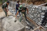 Personel TNI kerja bakti membangun plengsengan jalan dalam rangkaian program TMMD (TNI Manunggal Masuk Desa) di Desa Dompyong, Trenggalek, Jawa Timur, Selasa (16/7/2019). TMMD ke-105 di Trenggalek diikuti 150 personel TNI dan menyasar dua desa pedalaman setempat dengan fokus pengabdian pembangunan fisik (rabat jalan, penyediaan RTLH, rehab rumah ibadah) serta nonfisik yang meliputi kegiatan kerohanian, wawasan kebangsaan, penyuluhan narkoba dan lain sebagainya. Antara Jatim/Destyan Sujarwoko/zk.