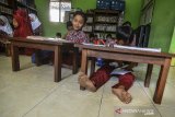 Siswa kelas 2 Sekolah Dasar Negeri (SDN) Cikadongdong mengikuti Kegiatan Belajar Mengajar (KBM) dilantai ruang perpustakaan di Singaparna, Kabupaten Tasikmalaya, Jawa Barat, Rabu (17/7/2018). Akibat kekurangan ruang kelas, sebanyak 19 siswa terpaksa belajar tidak menggunakan kursi, padahal pihak sekolah sudah kerap kali mengajukan kepada pemerintah setempat untuk menyediakan ruang kelas baru namun hingga saat ini belum terealisasi. ANTARA JABAR/Adeng Bustomi/agr