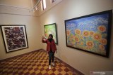 Pengunjung berswafoto dengan latar belakang batik lukis karya Komunitas Batik Lukis Jawa Timur yang dipajang saat pameran bertajuk 