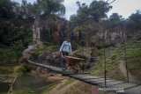 Warga melintasi Jembatan Gantung Cisanggarung, Cimenyan, Kabupaten Bandung, Jawa Barat, Jumat (19/7/2019). Pemerintah Provinsi Jawa Barat melalui Dinas Pemberdayaan Masyarakat dan Desa akan mulai membangun sebanyak 23 Jembatan Gantung Desa (Jantung Desa) yang tersebar di sejumlah Kabupaten/Kota di Jawa Barat. ANTARA JABAR/Raisan Al Farisi/agr