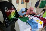 Pengrajin melukis tas selempang yang dipamerkan pada pekan kreatif 2019 di Taman Bustanulshalatin, Banda Aceh, Aceh, Jumat (19/7/2019). Tas selempang yang juga dikenal dengan sebutan otebag dilukis dengan motif menarik sebagai upaya mengurangi penggunaan kantong plastik saat berbelanja di pasar tradisional maupun modern. (Antara Aceh /Irwansyah Putra)