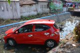 Warga melihat mobil Honda Brio masuk sungai setelah menabrak dua motor yang parkir di tepi Jalan Adityawarman Jombang, Jawa Timur, Senin (22/7/2019). Kecelakaan tersebut diduga disebabkan pengemudi belum mahir mengendarai mobil matic barunya, karena saat belok terlalu mengambil haluan ke kanan sehingga menabrak 2 motor yang sedang parkir. Tidak ada korban jiwa dalam peristiwa itu. Antara Jatim/Syaiful Arif/zk