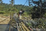 Warga menggendong anaknya menyeberangi Jembatan Gantung Cipangarangan, Desa Lengkongjaya yang melintasi Sungai Ciwulan, Kabupaten Tasikmalaya, Jawa Barat, Selasa (23/7/2019). Jembatan penghubung kecamatan Salawu dengan Kecamatan Cigalotang tersebut rusak parah, tetapi warga terpaksa melintasi karena menjadi akses utama dari Kampung Cibaeud dan sekitarnya. ANTARA JABAR/Adeng Bustomi/agr