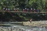 Siswa Sekolah Dasar (SD) menyeberangi Jembatan Gantung Cipangarangan, Desa Lengkongjaya yang melintasi Sungai Ciwulan, Kabupaten Tasikmalaya, Jawa Barat, Selasa (23/7/2019). Jembatan penghubung kecamatan Salawu dengan Kecamatan Cigalotang tersebut rusak parah, tetapi warga terpaksa melintasi karena menjadi akses utama dari Kampung Cibaeud dan sekitarnya. ANTARA JABAR/Adeng Bustomi/agr