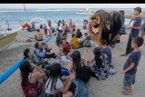 Wisatawan menyaksikan Tari Barong Bangkung dalam tradisi Ngelawang di Pantai Sanur, Denpasar, Bali, Kamis (25/7/2019). Tradisi Ngelawang tersebut merupakan rangkaian dari Hari Raya Galungan dan Kuningan yang dilakukan sekelompok remaja dengan membawakan Tari Barong Bangkung berkeliling desa sebagai ritual tolak bala. ANTARA FOTO/Nyoman Hendra Wibowo/nym.