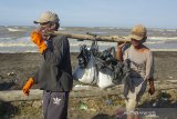 Warga membawa karung berisi pasir yang tercemar tumpahan minyak 