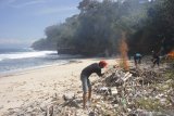 Penggiat Pokdarwis (Kelompok Sadar Wisata) membakar sampah kayu dan plastik yang mengotori pesisir Pantai Jung Pakis, Tulungagung, Jawa Timur, Kamis (25/7/2019). Kegiatan itu dilakukan secara swadaya untuk menjaga kebersihan pantai setempat. Antara Jatim/Destyan Sujarwoko/zk.