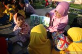 Seorang guru membacakan buku kepada murid-muridnya saat acara puncak Gerakan Nasional Orang Tua Membacakan Buku (Gernas Baku) di Taman Suroboyo, Surabaya, Jawa Timur, Sabtu (27/7/2019). Kegiatan yang diikuti sekitar 150 orang tua, guru dan murid Kelompok Belajar (KB) Taman Asuh Anak Muslim (TAAM) Avicenna tersebut bertujuan untuk menanamkan semangat mencintai dan membaca buku sejak dini kepada anak-anak. Antara Jatim/Moch Asim/zk.