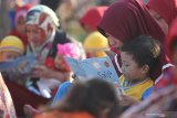 Salah satu orang tua membacakan buku kepada anaknya saat acara puncak Gerakan Nasional Orang Tua Membacakan Buku (Gernas Baku) di Taman Suroboyo, Surabaya, Jawa Timur, Sabtu (27/7/2019). Kegiatan yang diikuti sekitar 150 orang tua, guru dan murid Kelompok Belajar (KB) Taman Asuh Anak Muslim (TAAM) Avicenna tersebut bertujuan untuk menanamkan semangat mencintai dan membaca buku sejak dini kepada anak-anak. Antara Jatim/Moch Asim/zk.