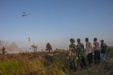 Lima anggota TNI/Polri dan Staf International Animal Rescue (IAR) Indonesia menyaksikan helikopter Badan Penanggulangan Bencana Daerah (BPBD) Ketapang memadamkan kebakaran lahan dengan cara water bombing di kawasan Ketapang Tanjungpura Km 4 di Desa Sungai Awan Kiri, Kecamatan Muara Pawan, Kabupaten Ketapang, Kalimantan Barat, Selasa (30/7/2019). Hingga kini belum diketahui secara pasti penyebab kebakaran yang menghanguskan puluhan hektar lahan yang berada tidak jauh dari lokasi pusat rehabilitasi Orangutan IAR Indonesia tersebut. ANTARA FOTO/HO/Humas IAR Indonesia-Heribertus/jhwANTARA FOTO/HERIBERTUS (ANTARA FOTO/HERIBERTUS)