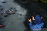 Warga memotret Sungai Cikiley yang tercemar di Antapani, Bandung, Jawa Barat, Jumat (2/8/2019).  Kondisi air aliran Sungai Cikiley yang bermuara di Sungai Citarum tersebut berubah warna dan mengeluarkan bau yang diduga akibat limbah industri sehingga menganggu aktivitas warga di sekitar sungai tersebut. ANTARA FOTO/Raisan Al Farisi/agr