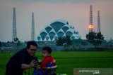 PROYEK PEMBANGUNAN MASJID AL JABBAR. Warga berswafoto dengan latar belakang matahari terbenam di proyek pembangunan Masjid Al Jabbar di Gedebage, Bandung, Jawa Barat, Kamis (1/8/2019). Pemerintah Provinsi Jawa Barat menargetkan Masjid Al Jabbar yang diproyeksikan dapat menampung 33.000 jamaah di atas lahan seluas 25,99 hektare tersebut akan dapat digunakan pada tahun 2020. ANTARA JABAR/Raisan Al Farisi/agr