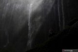 Pengunjung berfoto dengan latar Air Terjun Tumpak Sewu di Lumajang, Jawa Timur, Minggu (4/8/2019). Air Terjun Tumpak Sewu merupakan air terjun yang berketinggian sekitar 120 meter yang berada di perbatasan Lumajang dengan Malang. Antara Jatim/Zabur Karuru