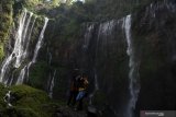 Pengunjung berswafoto dengan latar Air Terjun Tumpak Sewu di Lumajang, Jawa Timur, Minggu (4/8/2019). Air Terjun Tumpak Sewu merupakan air terjun yang berketinggian sekitar 120 meter yang berada di perbatasan Lumajang dengan Malang. Antara Jatim/Zabur Karuru