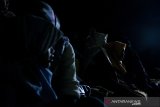 Relawan pembisik menceritakan visual adegan kepada anak tunanetra saat menonton film Keluarga Cemara pada kegiatan Bioskop Harewos di Nuart Sculpture Park, Bandung, Jawa Barat, Minggu (4/8/2019). Kegiatan tersebut bertujuan untuk menjembatani penyandang disabilitas anak khususnya tunanetra mampu menjadi masyarakat yang berbaur serta menikmati imajinasi visual yang ada dalam sebuah film. ANTARA FOTO/Novrian Arbi/agr