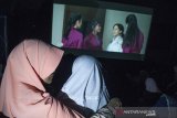 Relawan pembisik menceritakan visual adegan kepada anak tunanetra saat menonton film Keluarga Cemara pada kegiatan Bioskop Harewos di Nuart Sculpture Park, Bandung, Jawa Barat, Minggu (4/8/2019). Kegiatan tersebut bertujuan untuk menjembatani penyandang disabilitas anak khususnya tunanetra mampu menjadi masyarakat yang berbaur serta menikmati imajinasi visual yang ada dalam sebuah film. ANTARA FOTO/Novrian Arbi/agr