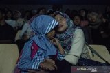 Relawan pembisik menceritakan visual adegan kepada anak tunanetra saat menonton film Keluarga Cemara pada kegiatan Bioskop Harewos di Nuart Sculpture Park, Bandung, Jawa Barat, Minggu (4/8/2019). Kegiatan tersebut bertujuan untuk menjembatani penyandang disabilitas anak khususnya tunanetra mampu menjadi masyarakat yang berbaur serta menikmati imajinasi visual yang ada dalam sebuah film. ANTARA FOTO/Novrian Arbi/agr