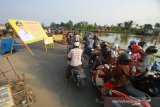 Pengendara sepeda motor melintas di jembatan darurat Sungai Gardu Banjarmasin, Kalimantan Selatan, Rabu (7/8/2019).Proyek pembangunan jembatan penghubung antara kota Banjarmasin dan kabupaten Banjar dengan anggaran 17,5 miliar mulai dikerjakan.Foto Antaranews Kalsel/Bayu Pratama S.