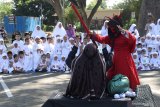 Guru memperagakan nabi Ibrahim yang diganggu setan di hadapan sejumlah anak saat menceritakan asal mula ibadah kurban dan haji di Tirtoyoso, Kota Kediri, Jawa Timur, Jumat (9/8/2019). Kegiatan yang diikuti sedikitnya 300 anak tingkat PAUD dan TK yayasan taman pendidikan Rahmat tersebut bertujuan memperkenalkan rukun islam ke lima kepada anak sejak dini. Antara Jatim/Prasetia Fauzani/zk