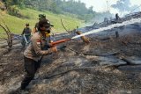 SINERGI TANGGULANGI KARHUTLA DI PERBATASAN. Petugas Polsek Entikong Bripda Indah Roida Simaremare (kiri) bersama dua anggota TNI dari Koramil Entikong menyemprotkan air ke tanah lokasi kebakaran hutan dan lahan di Desa Nekan, Kecamatan Entikong, Kabupaten Sanggau, Kalimantan Barat, Rabu (7/8/2019). Tim gabungan petugas TNI/Polri dari Polsek dan Koramil Entikong bersinergi dalam menanggulangi karhutla yang berasal dari aktivitas buka lahan dengan cara dibakar yang dilakukan masyarakat setempat di kawasan perbatasan Indonesia-Malaysia. ANTARA FOTO/Agus Alfian/jhwANTARA FOTO/AGUS ALFIAN (ANTARA FOTO/AGUS ALFIAN)