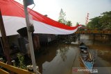 Perahu bermesin melintas di sungai duyung kuin cerucuk yang terbentang bendera merah putih di Banjarmasin, Kalimantan Selatan, Minggu (11/8/2019).Dalam rangka menyemarakkan HUT ke-74 Republik Indonesia warga kuin cerucuk Banjarmasin memasang bendera Merah Putih sepanjang 100 meter diatas sungai Duyung Kuin Cerucuk dan berbagai macam pernak pernik kemerdekaan.Foto Antaranews Kalsel/Bayu Pratama S.