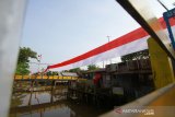 Warga melintas di bendera merah putih yang terbentang di sungai duyung kuin cerucuk, Banjarmasin, Kalimantan Selatan, Minggu (11/8/2019).Dalam rangka menyemarakkan HUT ke-74 Republik Indonesia warga kuin cerucuk Banjarmasin memasang bendera Merah Putih sepanjang 100 meter diatas sungai Duyung Kuin Cerucuk dan berbagai macam pernak pernik kemerdekaan.Foto Antaranews Kalsel/Bayu Pratama S.