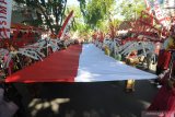 Peserta membawa bendera merah putih berukuran besar saat Karnaval Budaya di Pamekasan, Jawa Timur, senin (12/8/2019). Karnaval yang diikuti sekolah dari tingkat SD sampai SMA yang bertema 