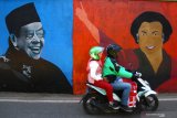 Seorang pengemudi ojek online melintas di depan mural mantan Presiden RI, KH Abdurrahman Wahid dan Megawati Soekarno Putri  di Sukun, Malang, Jawa Timur, Senin (12/8/2019). Mural presiden dan mantan presiden tersebut sengaja di gambar warga setempat untuk menyambut HUT Kemerdekaan RI Ke-74. Antara Jatim/Ari Bowo Sucipto/zk.