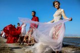 Model mengenakan busana kebaya bertema merah putih saat fashion show di tanggul lapindo Porong, Sidoarjo, Jawa Timur, Selasa (13/8/2019). Peragaan busana yang menampilkan busana kebaya tersebut untuk memeriahkan HUT ke-74 kemerdekaan RI. Antara Jatim/Umarul Faruq/zk