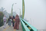 Umat Muslim yang akan menunaikan ibadah Salat Idul Adha berjalan di tepian Sungai Kapuas yang diselimuti kabut asap di Pontianak, Kalimantan Barat, Minggu (11/8/2019). Umat Muslim di Pontianak melaksanakan salat Idul Adha dalam kondisi diselimuti kabut asap pekat yang berasal dari kebakaran hutan dan lahan. ANTARA FOTO/Jessica Helena WuysangANTARA FOTO/JESSICA HELENA WUYSANG (ANTARA FOTO/JESSICA HELENA WUYSANG)