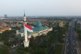 Foto aerial masyarakat melihat pengibaran bendera Merah Putih super akbar di menara Masjid Al Akbar Surabaya, Kamis, (15/08/2019). Pengibaran bendera Merah Putih dengan berat 45 kilogram tersebut dilakukan oleh 99 orang dalam rangka menyambut HUT ke-74 Kemerdekaan Republik Indonesia. Antara Jatim/Naufal Ammar/zk.