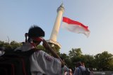 Pelajar melakukan penghormatan pada bendera Merah Putih yang berkibar di menara  Masjid Al Akbar Surabaya, Jawa Timur, Kamis (15/8/2019). Pengibaran Bendera Merah Putih berukuran panjang 25 meter dan lebar 17 meter itu dalam rangka menyambut HUT ke-74 Kemerdekaan Republik Indonesia. Antara Jatim/Didik Suhartono/ZK