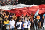 Sejumlah pemuda dan pemudi mengarak kain warna merah dan putih melewati jalan protokol di Kota Kediri, Jawa Timur, Jumat (16/8/2019).Kain yang terbagi dalam sejumlah potongan tersebut akan disatukan menjadi bendera merah putih raksasa selebar 35 meter x 55 meter dan akan dikibarkan di atas pegunungan klotok guna memperingati HUT ke-74 kemerdekaan bangsa Indonesia. Antara Jatim/Prasetia Fauzani/zk