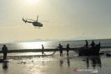 Helikopter melintas saat nelayan tradisional menarik pukat darat di Pantai Kampung Jawa, Banda Aceh, Aceh, Minggu (18/8/2019). Helikopter Mess Crew Polda Aceh melakukan aksi terbang rendah dan menjadi tontonan menarik bagi pengunjung sekitar. Antara Foto/Indra Wijaya.