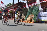 Pebalap sepeda melintas di dekat dadak merak (bagian dari seni Reog Ponorogo) sesaat sebelum pemberangkatan pebalap pada etape kedua Tour de Indonesia 2019 di Kota Madiun, Jawa Timur, Selasa (20/8/2019). Seni Reog Ponorogo menghibur pebalap dan masyarakat di lokasi pemberangkatan etape kedua Tour De Indonesia di dari Alun-alun Kota Madiun. Etape kedua balap sepeda tersebut menempuh jarak 163,4 kilometer dimulai dari Madiun, Jawa Timur dan berakhir di Kota Batu, Jawa Timur. Antara Jatim/Siswowidodo/zk