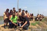 Sejumlah murid bersama tim Pertagas menaman Pohon Trembesi di Desa Penatarsewu, Sidoarjo, Jawa Timur, Jumat (23/8/2019). Penanaman Pohon Trembesi tersebut  dilakukan dalam rangka membantu mengurangi tingkat pencemaran di Kampung Ikan Asap akibat aktivitas pengasapan ikan. Antara Jatim/Pertagas/ZK