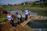 Sejumlah siswa SMPN Baleendah II menyeberangi Sungai Citarum menggunakan perahu eretan di Bojongsoang, Kabupaten Bandung, Jawa Barat, Rabu (28/8/2019). Menko Bidang Kemaritiman Luhut Binsar Panjaitan menyatakan, program Citarum Harum di tiga sektor telah mencapai 60 persen dan ditargetkan akan pulih pada 2025 mendatang. ANTARA JABAR/Raisan Al Farisi/agr