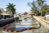 Warga melintas di sekitar tumpahan minyak mentah di Desa Cemarajaya, Cibuaya, Karawang, Jawa Barat, Jumat (30/8/2019). Badan Meteorologi, Klimatologi dan Geofisika (BMKG) mengatakan dapat membantu Pertamina untuk memetakan sebaran tumpahan minyak mentah di perairan laut utara Karawang berdasarkan penjalaran gelombang laut. ANTARA FOTO/M Ibnu Chazar/agr