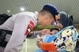 Seorang personil Brimob Polda Kalbar membelai anak yang digendong istrinya sesaat sebelum keberangkatan pasukan Bantuan Kendali Operasi (BKO) Brimob di Bandara Supadio, Kabupaten Kubu Raya, Kalimantan Barat, Kamis (29/8/2019) malam. Polda Kalbar mengirim 250 personil Brimob ke Papua untuk melaksanakan tugas pengamanan pasca konflik di daerah tersebut. ANTARA FOTO/Jessica Helena WuysangANTARA FOTO/JESSICA HELENA WUYSANG (ANTARA FOTO/JESSICA HELENA WUYSANG)