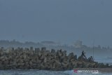 Warga memancing ikan di atas beton pemecah ombak atau breakwater di Pantai Barat, Kampung Pananjung, Kabupaten Pangandaran, Jawa Barat, Senin (2/9/2019). Tanggul pemecah ombak tersebut dibangun di beberapa titik kawasan pesisir Pantai Pangandaran untuk mencegah bahaya abrasi dan wisatawan memanfaatkan kawasan tersebut untuk berswafoto sambil menikmati matahari terbenam. ANTARA FOTO/Adeng Bustomi/ANTARA FOTO/ADENG BUSTOMI (ANTARA FOTO/ADENG BUSTOMI)