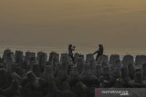 Wisatawan swafoto di atas beton pemecah ombak atau breakwater di Pantai Barat, Kampung Pananjung, Kabupaten Pangandaran, Jawa Barat, Senin (2/9/2019). Pemasangan beton pemecah ombak di beberapa titik di kawasan pesisir Pantai Pangandaran tersebut untuk mencegah abrasi dan kerap kali dijadikan lokasi swafoto oleh wisatawan sambil menikmati matahari terbenam. ANTARA FOTO/Adeng Bustomi/agr