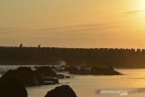 Wisatawan swafoto di atas beton pemecah ombak atau breakwater di Pantai Barat, Kampung Pananjung, Kabupaten Pangandaran, Jawa Barat, Senin (2/9/2019). Pemasangan beton pemecah ombak di beberapa titik di kawasan pesisir Pantai Pangandaran tersebut untuk mencegah abrasi dan kerap kali dijadikan lokasi swafoto oleh wisatawan sambil menikmati matahari terbenam. ANTARA FOTO/Adeng Bustomi/agr