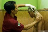 Petugas memandikan pasien ODGJ (Orang Dengan Gangguan Jiwa) korban pasung bernama Asman Budi (40) di RSUD dr Soedomo, Trenggalek, Jawa Timur, Senin (2/9/2019). Sejak 2017 hingga sekarang, Pemkab Trenggalek telah membebaskan 150 orang dari total 153 korban pasung yang ada di daerah itu dan ditargetkan bebas pasung 100 persen pada akhir 2019. Antara Jatim/Destyan Sujarwoko/zk.