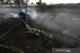 Relawan pemadam kebakaran melakukan pemabasahan terhadap kendaraan roda dua yang terbakar akibat kebakaran lahan gambut di Desa Pengayuan, Kecamatan Liang Anggang, Banjarbaru, Kalimantan Selatan, Jumat (6/9/2019).Ratusan hektar lahan gambut di kawasan Liang Anggang terbakar hingga mendekati permukiman penduduk di wilayah setempat.Foto Antaranews Kalsel/Bayu Pratama S.