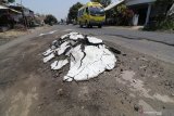 Bus melintas di jalan rusak perbatasan Kediri - Blitar di Desa Tawang, Kediri, Jawa Timur, Sabtu (14/9/2019). Sejumlah titik jalan di daerah itu terkelupas dan berlubang karena sering dilalui truk penambangan pasir dari gunung Kelud yang melebihi ambang batas tonase. Antara Jatim/Prasetia Fauzani/zk.