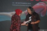 Kepala Divisi Galeri Foto Jurnalistik Antara (GFJA) Oscar Motuloh (kanan) menyerahkan buku Pameran dan Art & Diplomacy kepada Wali Kota Surabaya Tri Rismaharini (kiri) saat pembukaan pameran foto Sportacular di Gedung Siola (Surabaya Museum), Surabaya, Jawa Timur, Sabtu (21/9/2019). Pameran yang memajang 68 foto karya 37 pewarta tersebut menampilkan foto-foto Asian Games dan Asian Para Games 2018 serta beberapa olahraga tradisonal Nusantara. Antara Jatim/Saiful Bahri/zk.