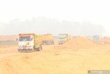 Sejumlah truk melintasi lokasi proyek pembangunan Terminal Kijing yang diselimuti kabut asap di Kabupaten Mempawah, Kalimantan Barat, Kamis (19/9/2019). General Manager Cabang Pontianak PT Pelindo II (Persero)/IPC Adi Sugiri menyatakan kemajuan dari tahap pertama pembangunan Terminal Kijing yang merupakan pelabuhan berstandar internasional terbesar di Kalimantan tersebut mencapai 23 persen dan ditargetkan pada pertengahan 2020 sudah beroperasi. ANTARA FOTO/Jessica Helena Wuysang