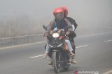 Seorang anak yang di bonceng terpaksa menutup wajahnya saat melintas di jalan Lingkar Selatan yang diselimuti kabut asap pekat di  Banjarbaru, Kalimantan Selatan, Rabu (25/9/2019).Kebakaran hutan dan lahan (Karhutla) menyebabkan timbulnya kabut asap pekat yang berdampak kepada kesehatan warga, terganggunya aktivitas dengan jarak pandang terbatas serta menimbulkan aroma menyengat. Foto Antaranews Kalsel/Bayu Pratama S.